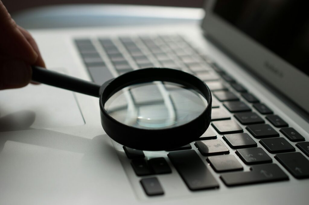 Magnifying glass beside a grey laptop computer, illustrating how people search online