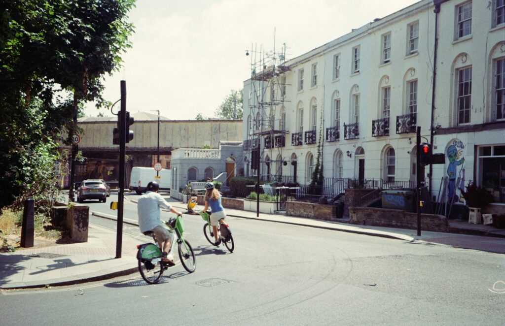 Cycling on green rental bikes past white townhouses, a cleaner way to travel through cities