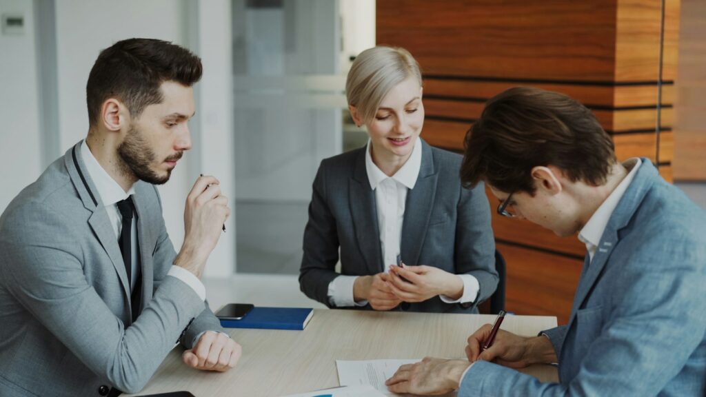 Business people signing a contract at a table in a modern office