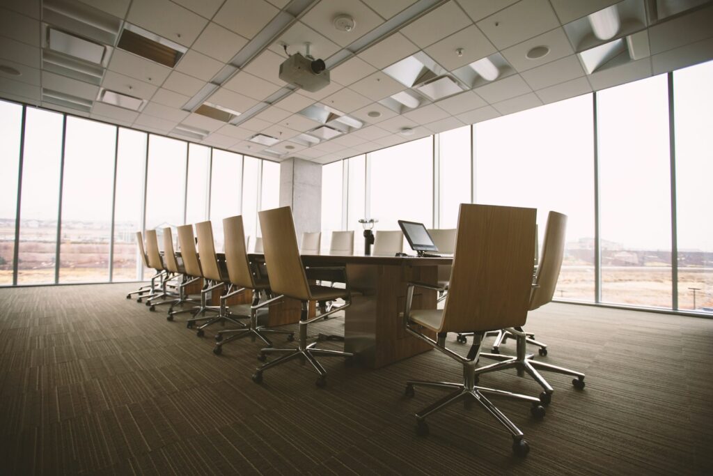 Oval wooden conference table surrounded by chairs inside a conference room