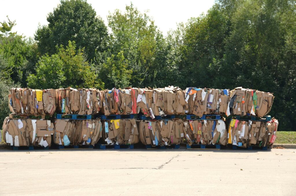 Stacked bales of compressed cardboard on blue pallets waiting to be taken for recycling