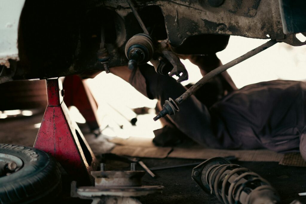 Mechanic working underneath a car in a busy garage workshop