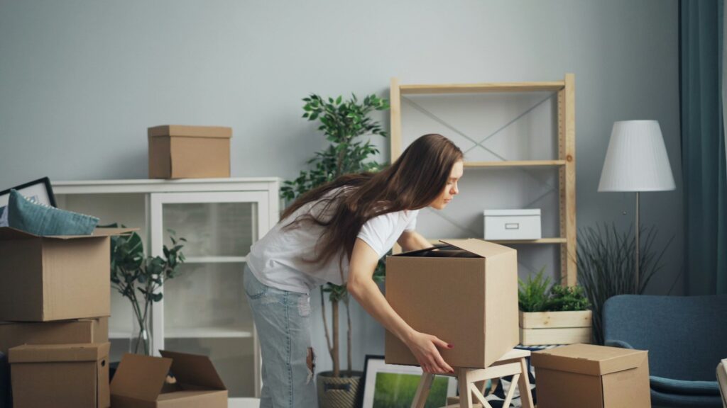 Woman carrying boxes through a living room while packing up for a house move