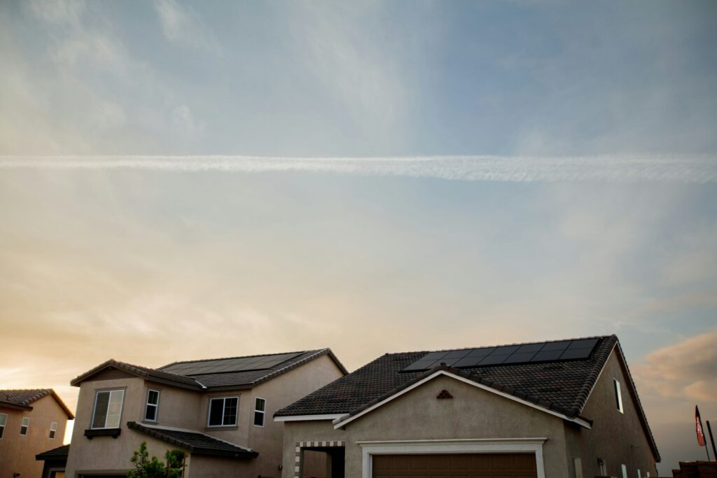 Solar panels on the roof of two homes beneath a blue sky