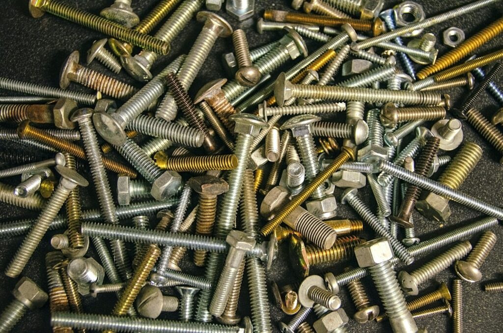 Assorted silver bolts on a wooden table, the kind of metal parts that get plated