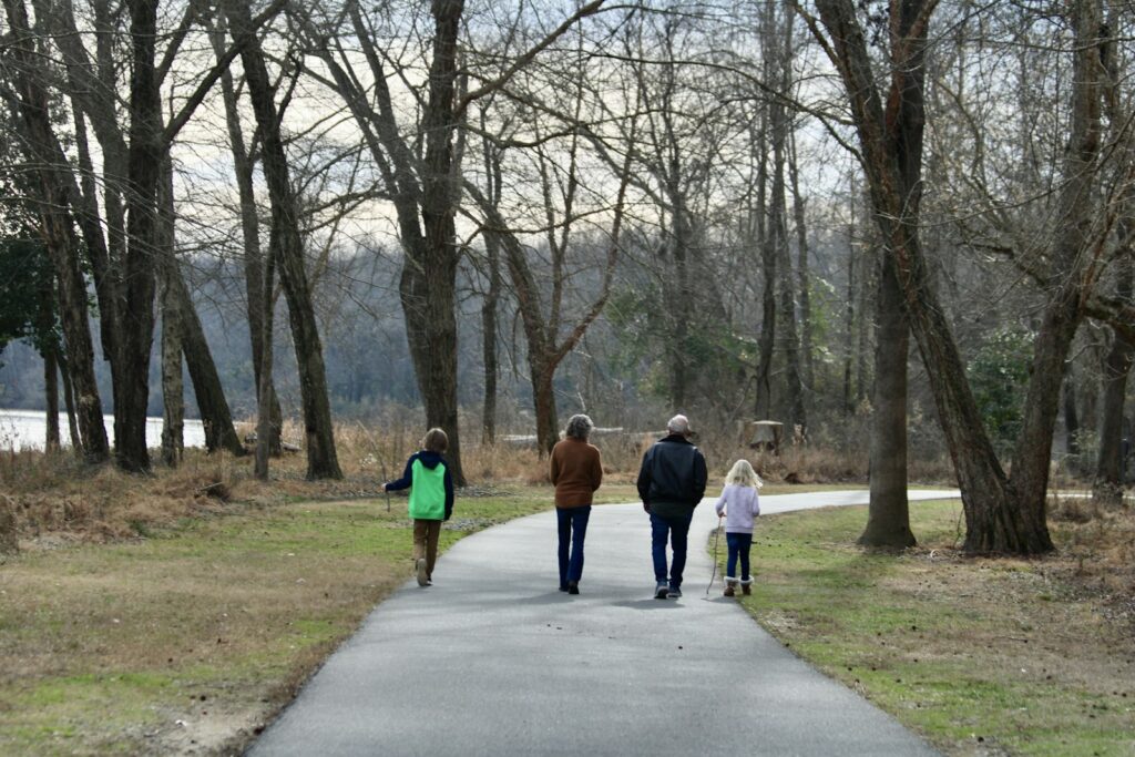 Family walking together along a path in a park, showing everyday life that fostering can fit into